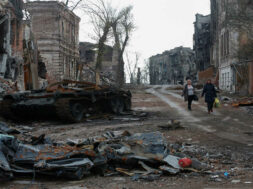 People walk near damaged buildings in Mariupol