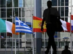 A pedestrian walks towards the Irish, Greek, Spanish, French and Dutch national flags outside the European Parliament in Brussels
